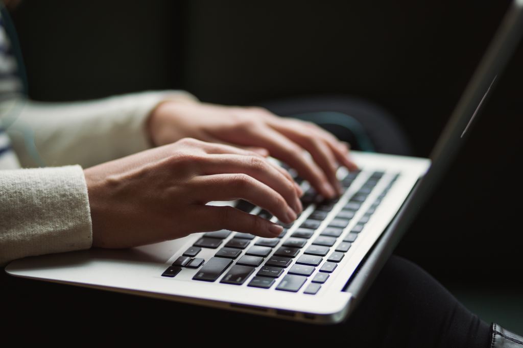 Image of a woman's hands, typing on a laptop
